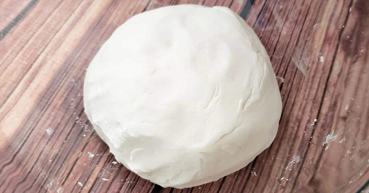 Ball of white cloud dough in glass bowl.